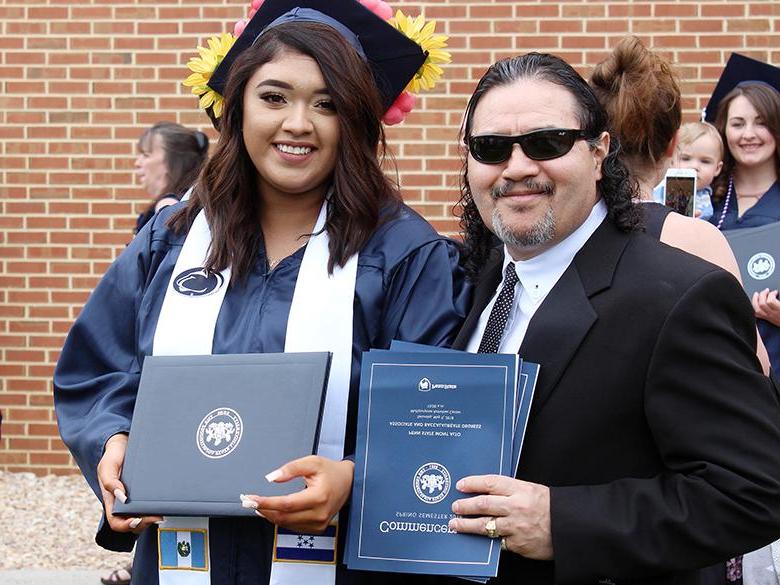 年轻的女毕业生和她的父亲在毕业典礼上合影